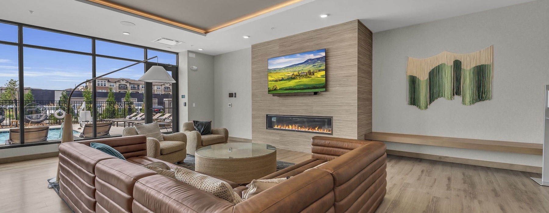 A residential lounge area with a couch, chairs, and a flatscreen television at Darby at Briarcliff apartments in Briarcliff Kansas City.